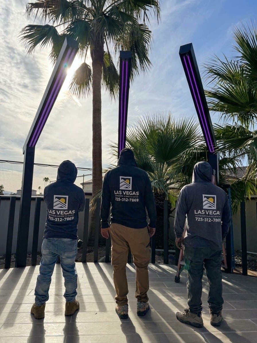 Three of our crew, seen from behind in Las Vegas Outdoor Shade & Patio hoodies, beside newly installed aluminum posts