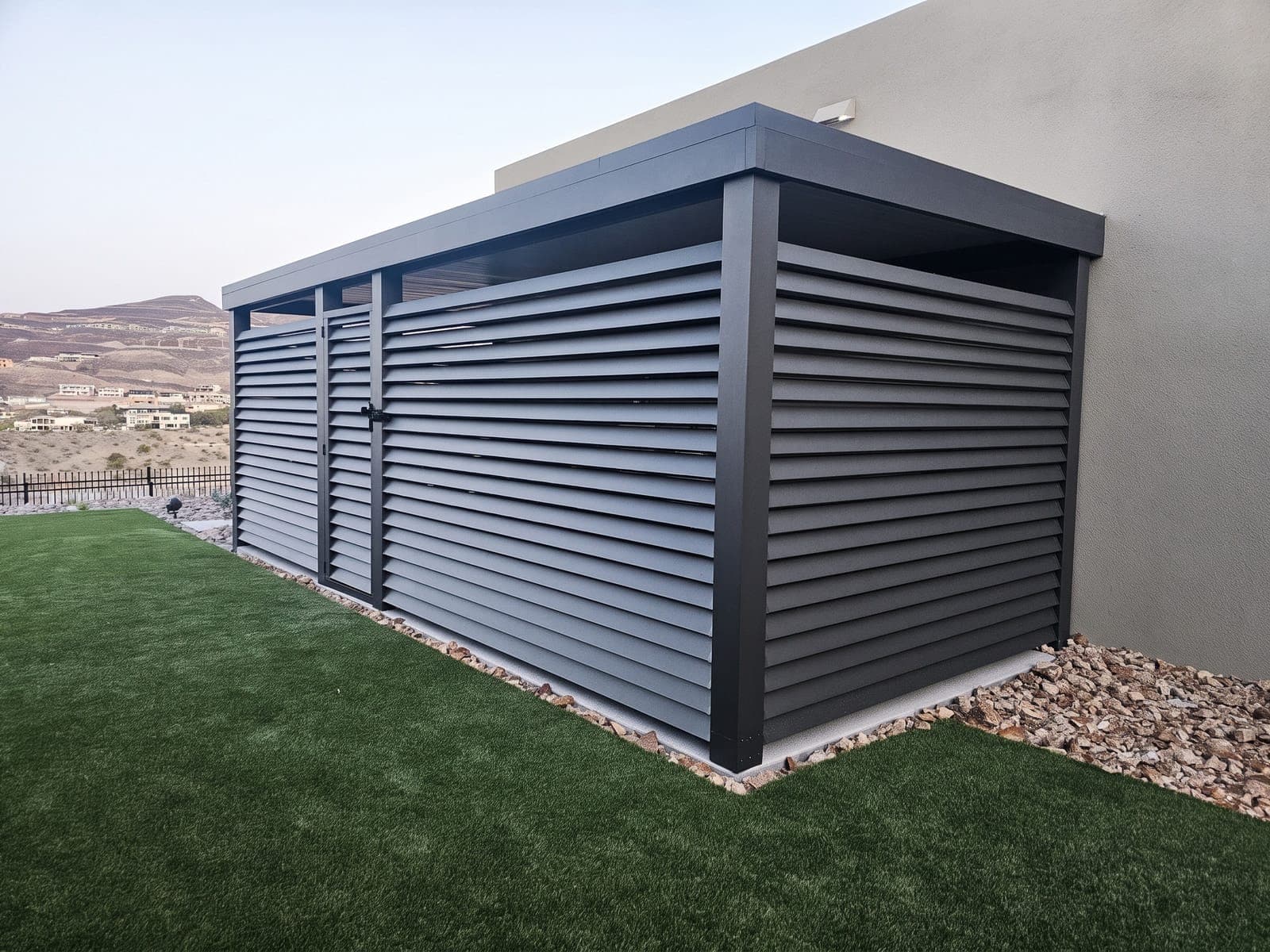 Gray louvered 4K Aluminum side-yard enclosure with a matching door and a solid roof against a modern home