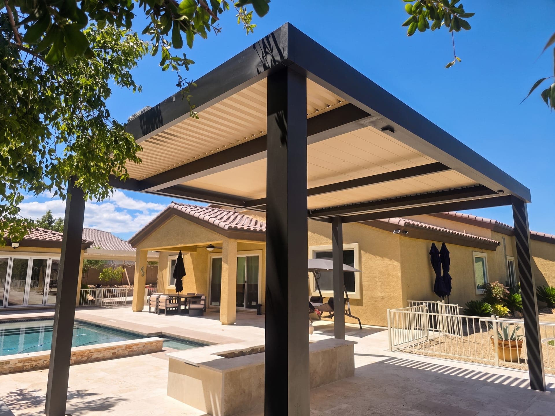 Freestanding 4K Aluminum louvered pergola with a dark frame and tan blades on a travertine patio beside a pool